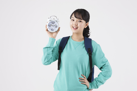 Asian female high school student with clock isolated on whiteの写真素材