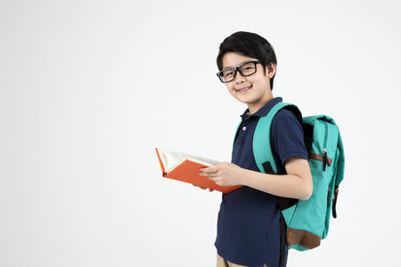 Asian elementary school boy reading book isolated on white