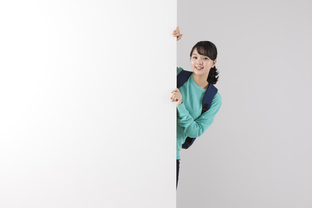 Asian female high school student behind the wall isolated on whiteの写真素材