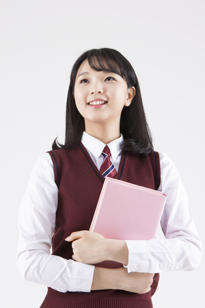 Asian female high school student with book isolated on whiteの写真素材