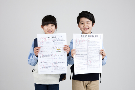 Asian elementary school students with perfect score test paper isolated on white