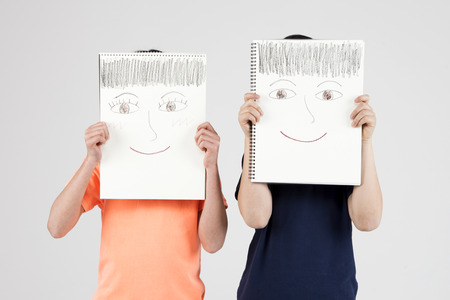 Asian elementary school students with face drawing isolated on whiteの写真素材