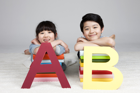 Asian elementary school students with alphabet a, b panel isolated on whiteの写真素材