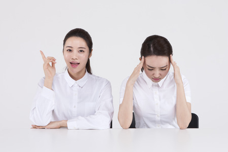 Asian two women with headache and idea isolated on whiteの写真素材