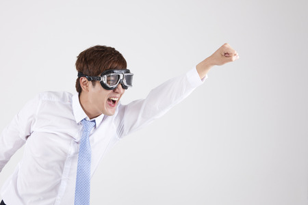 Asian young man in suit in flying motion with goggles isolated on whiteの写真素材