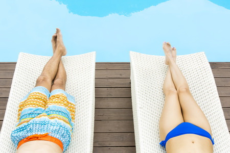 Asian happy couple in swim wear lying on sun bed at pool