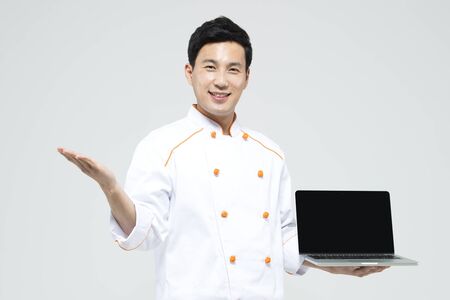 Asian male chef with laptop isolated on whiteの写真素材
