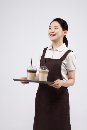 Asian female part time worker serving coffee isolated on whiteの写真素材