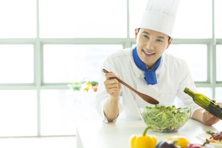 Asian male chef making salad isolated on whiteの写真素材
