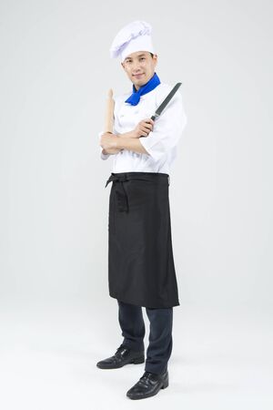 Asian male chef with cooking knives and push stick isolated on whiteの写真素材