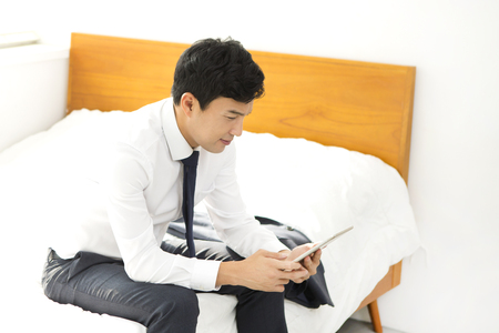Asian young man using tablet pc on bedroomの写真素材