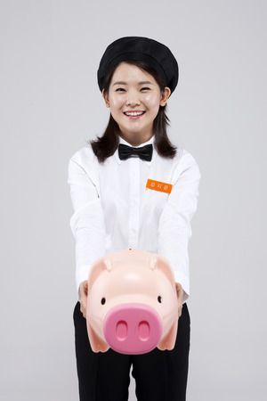 Asian female part time worker with piggy bank isolated on whiteの写真素材