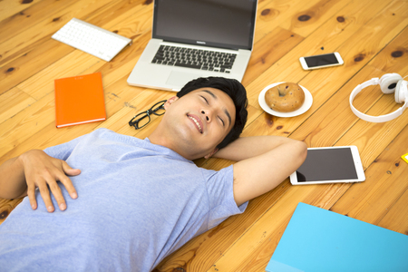 Asian young man lying back with itemsの写真素材