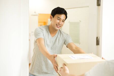 Asian young man receiving the packageの写真素材