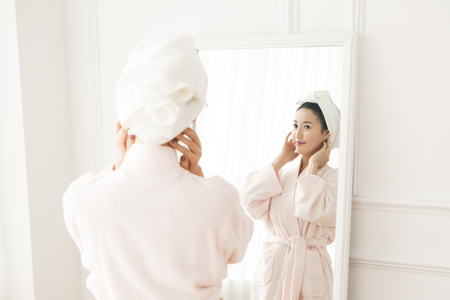 Asian beautiful woman in shower gown looking at mirrorの写真素材