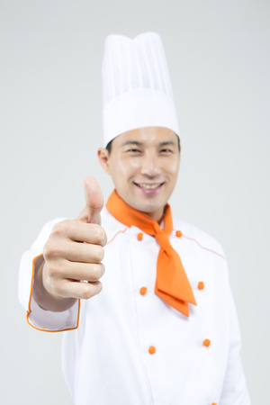 Asian male chef in thumb up gesture isolated on whiteの写真素材