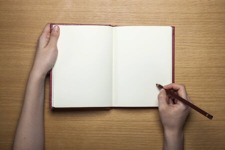 Hand writing open notebook on wooden tableの写真素材