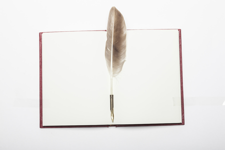 Feather quill and notebook isolated on whiteの写真素材