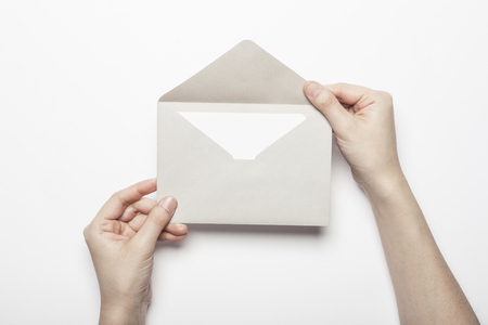 Hand opening grey envelope isolated on whiteの写真素材
