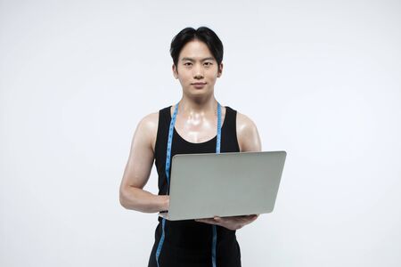 Asian fitness man with laptop isolated on whiteの写真素材