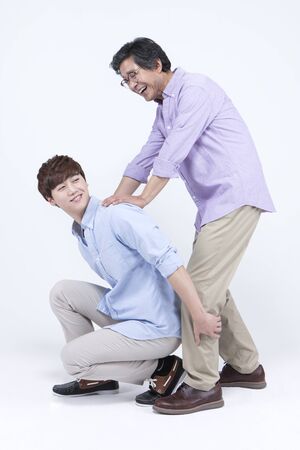 Asian man carrying father on his back isolated on whiteの写真素材