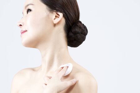 Asian beautiful woman applying powder isolated on whiteの写真素材