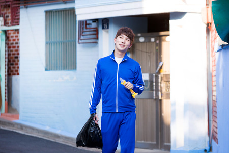 Asian man in training clothes eating ice candy