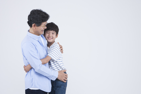 Asian grandfather and grandson hugging isolated on whiteの写真素材