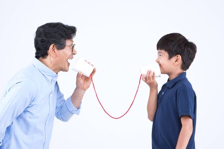 Asian grandfather and grandson with paper cup phone isolated on white