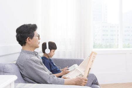 Asian grandfather and grandson with tablet pc and newspaperの写真素材