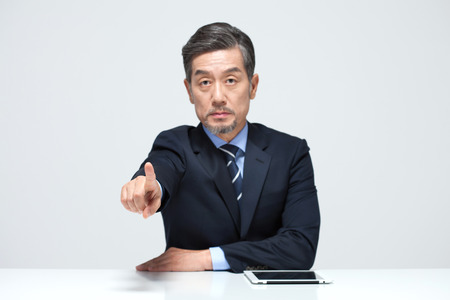 Asian man in suit pointing isolated on whiteの写真素材