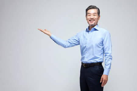 Asian man in suit pointing isolated on whiteの写真素材
