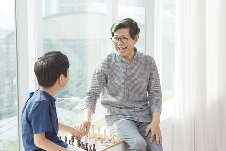 Asian grandfather and grandson playing chessの写真素材
