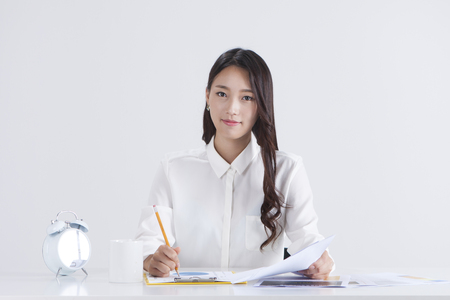 Asian woman writing something isolated on whiteの写真素材