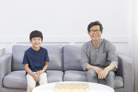 Asian grandfather and grandson playing Korea chess
