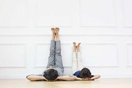 Asian grandfather and grandson putting leg on the wallの写真素材