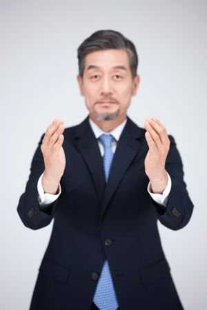 Asian man in suit holding gesture isolated on whiteの写真素材
