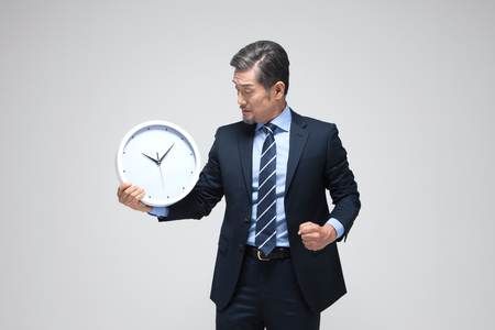 Asian man with clock isolated on whiteの写真素材