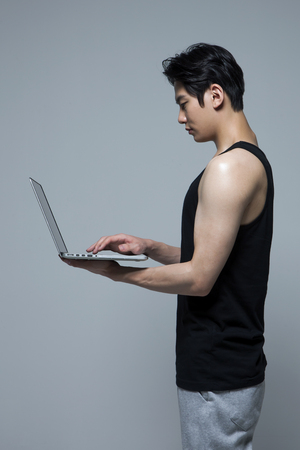 Asian fitness man with laptop isolated on whiteの写真素材
