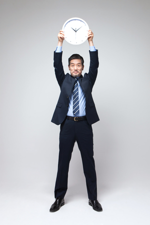 Asian man in suit with clock isolated on whiteの写真素材