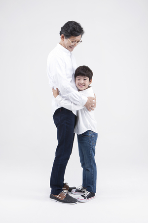 Asian grandfather and grandson hugging isolated on whiteの写真素材