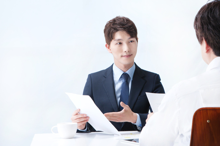Asian man in suit working isolated on whiteの写真素材