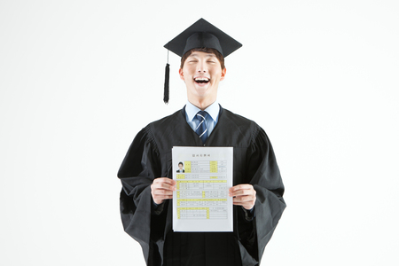 Asian man in graduation clothes with resume isolated on whiteの写真素材