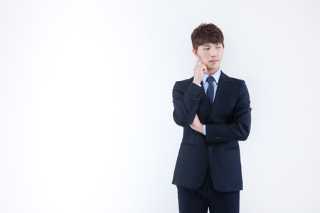 Asian man in suit thinking isolated on whiteの写真素材