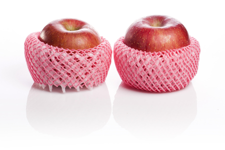 Two red ripe apples in a fruit net isolated on white backgroundの写真素材