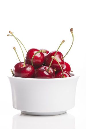 Cherries in a white bowl isolated on white backgroundの写真素材