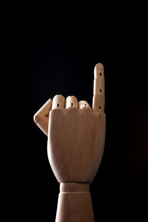 A wooden ball-jointed right hand isolated on black background makes a little finger promise with palm backward.の写真素材
