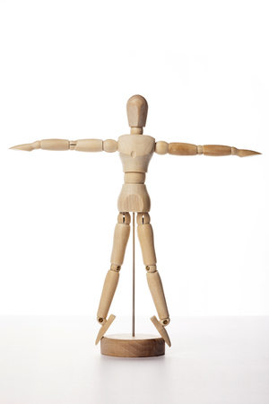 A wooden ball-jointed doll isolated on white background shows a person standing forward with arms stretched side to side.の写真素材