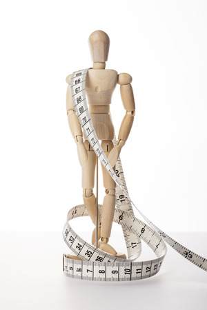 A wooden ball-jointed doll isolated on white background shows a person bounded with a tape measure.の写真素材