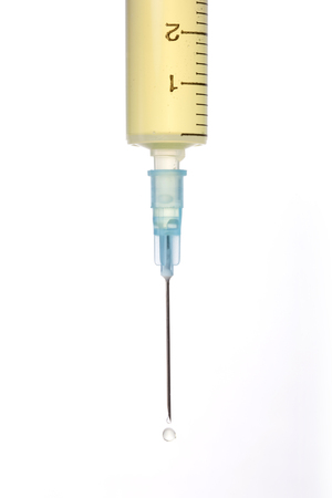 A laboratory syringe on white background is filled with yellow solution.の写真素材
